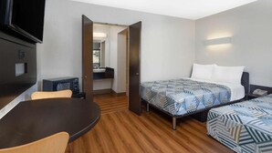 A hotel room with a bed, two bedside tables, a desk with a chair, a TV, and a microwave. - Vagabond Inn - Santa Barbara (Santa Barbara)