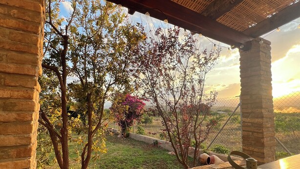 Una habitación con vistas a árboles y al atardecer, un pilar de piedra y un farol en la mesa.