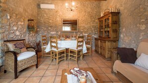 Un comedor rústico con pared de piedra, mesa de madera, sillas y un aparador.