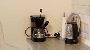 Et køkken med kaffemaskine, elkedel og komfur.
