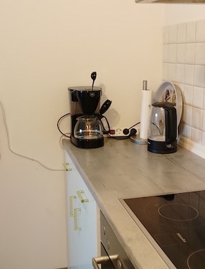 A kitchen with a coffee maker, a kettle, and a stove. - Beautiful Apartment in the Rhön (Kaltennordheim)