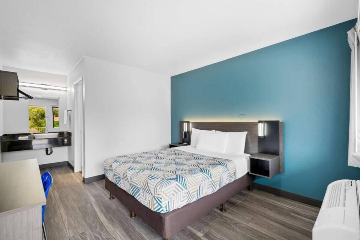 Une chambre d’hôtel avec un lit, des tables de chevet, un bureau et une chaise.