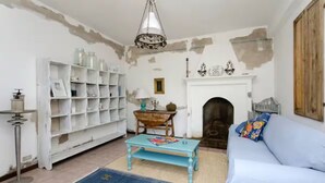 Un soggiorno con una libreria bianca, un divano blu, un tavolo in legno e un camino.