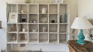 Un mobiletto bianco con diversi oggetti, tra cui vasetti, una teiera e una lampada.