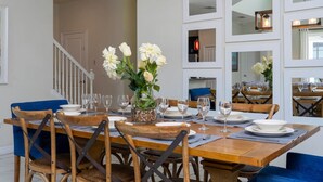 A dining area with a wooden table set for six, surrounded by blue chairs, with a vase of white flowers in the center. - Modern 5BR Oasis Near Disney - Pvt pool - 4712SL (Kissimmee)