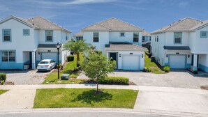 A row of white two-story houses with tiled roofs, a central tree, and a parked car. - Modern 5BR Oasis Near Disney - Pvt pool - 4712SL (Kissimmee)