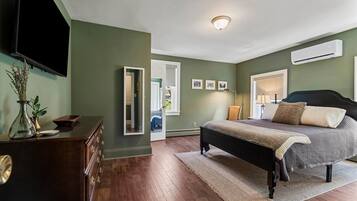 Une chambre à coucher comprenant un lit, une commode, un miroir et un appareil de climatisation fixé au mur.