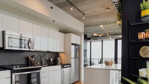 Une cuisine moderne avec des meubles blancs, des appareils en acier inoxydable et un îlot central.