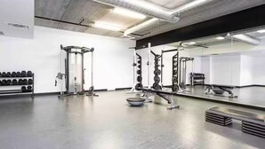 Une salle de sport équipée de matériel de musculation, dotée d’un mur avec des miroirs et d’un porte-haltères.