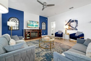 Ein Wohnzimmer mit Kamin, blauen Wänden, einem Deckenventilator und zwei Sofas.