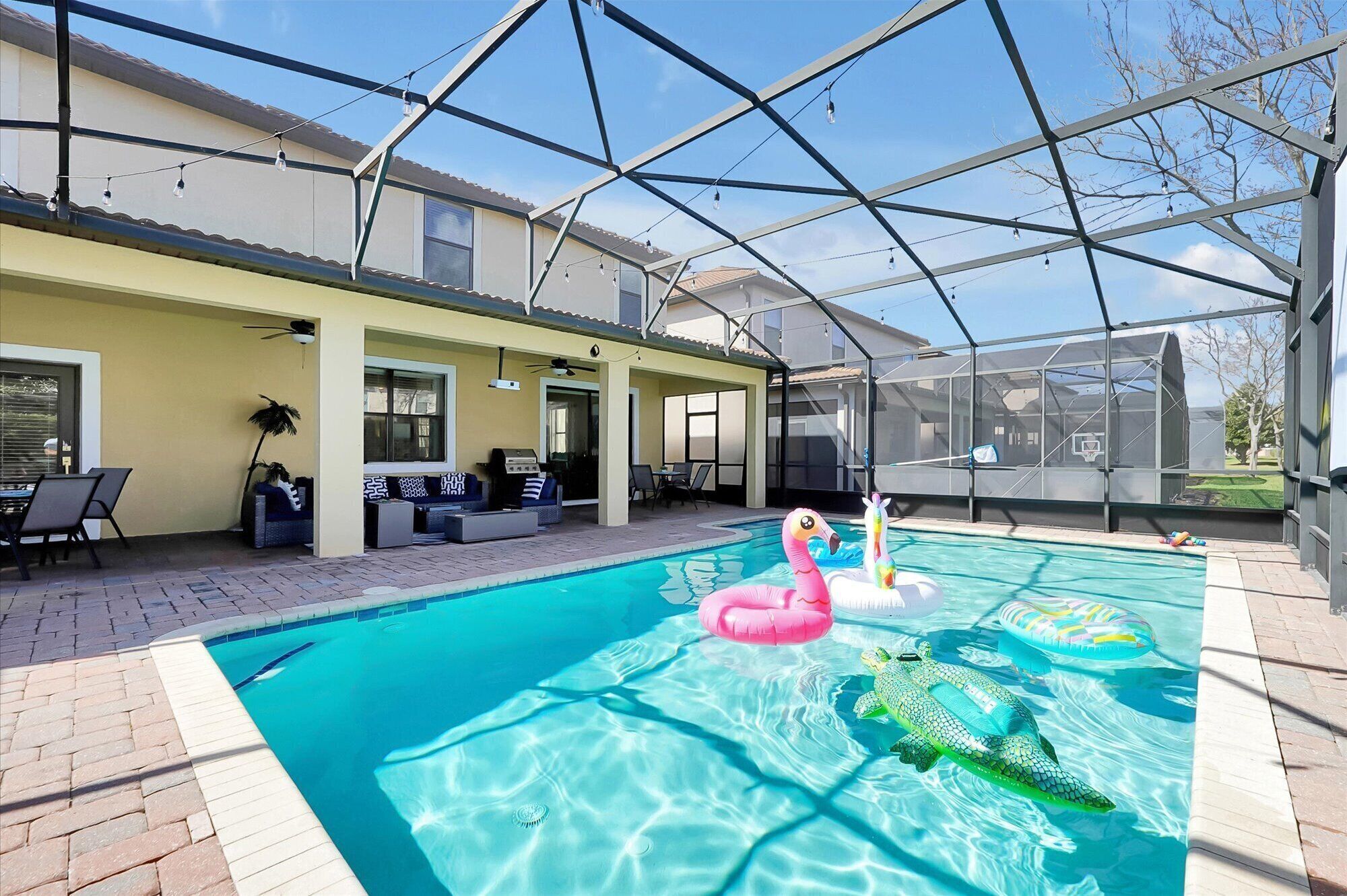 Una piscina con giochi gonfiabili, un patio coperto e una casa sullo sfondo.