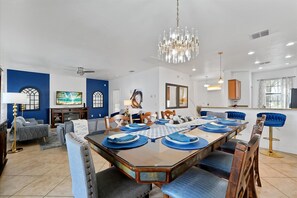 Un comedor con una mesa grande dispuesta para seis personas, rodeada de sillas tapizadas en azul.