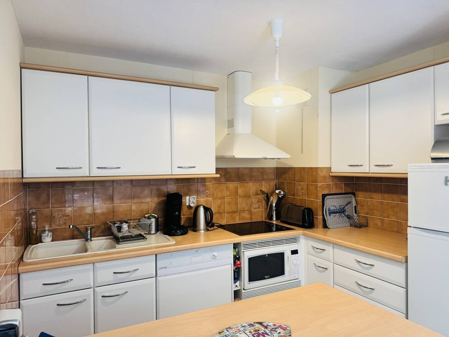 A modern kitchen with white cabinets, a microwave, a kettle, and a toaster.