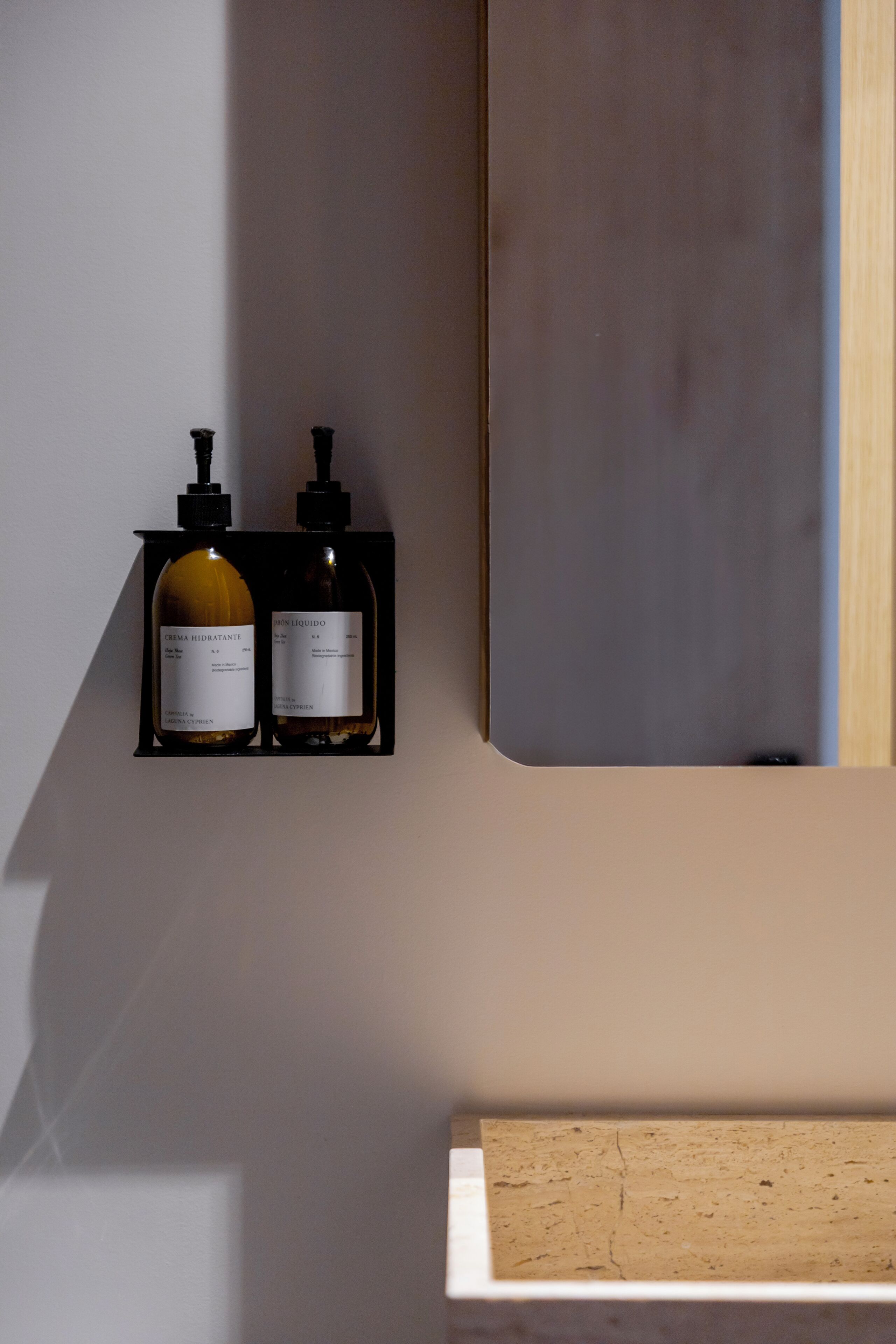 Een wandplank met twee flessen, waarvan één gelabeld is 'CREMA HIDRATANTE' en de andere 'LIQUIDO'.