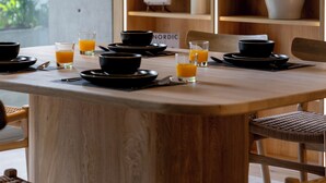 Ein Holztisch mit schwarzen Schüsseln und Gläsern Orangensaft, umgeben von Korbstühlen.