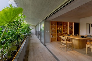 A modern kitchen with a wooden island, built-in shelves, and a view of a garden.
