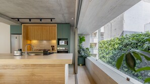 Eine moderne Küche mit Holzschränken, einer Spüle aus Edelstahl und Blick auf einen Balkon mit Grünpflanzen.