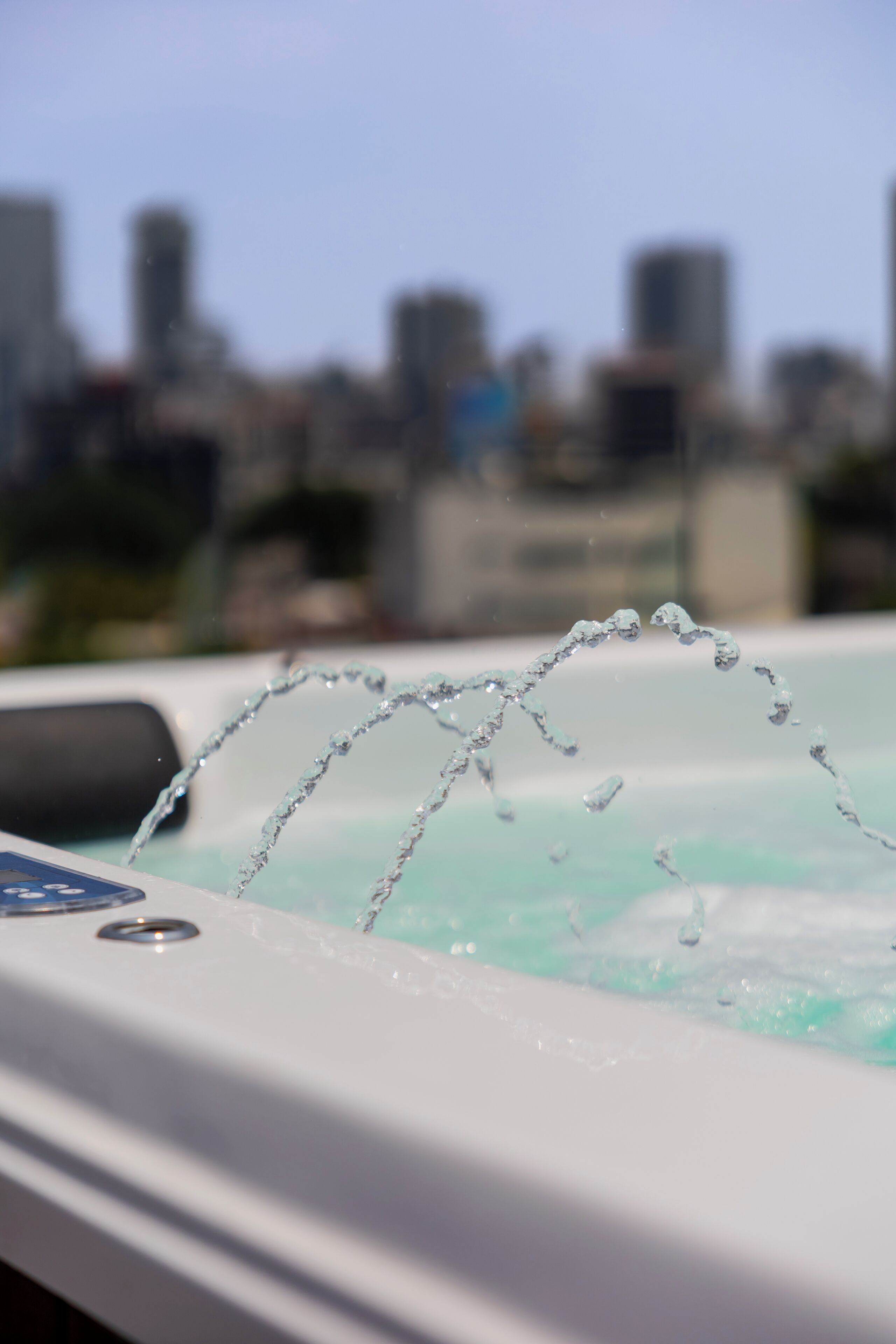 Un bain à remous avec des jets d’eau en mouvement, sur fond d’une silhouette floue de paysage urbain.