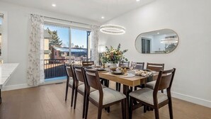 Comedor con una mesa dispuesta para seis, una araña, un espejo grande y vistas al exterior.