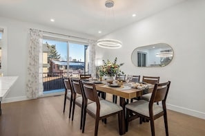 Comedor con una mesa dispuesta para seis, una araña, un espejo grande y vistas al exterior.