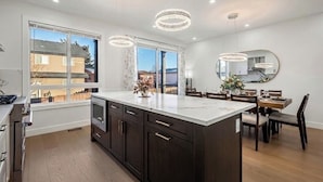 Una cocina moderna con una isla grande, muebles oscuros e iluminación colgante.