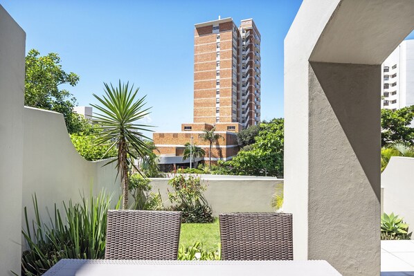 Un immeuble de grande hauteur au design moderne, entouré de verdure et surplombant un ciel dégagé.