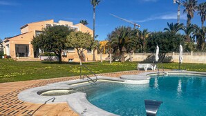 A swimming pool with a unique design, surrounded by a brick deck and palm trees.