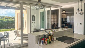 A modern kitchen with a large island, a dining area with chairs, and a view of the outdoors.