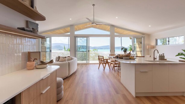 Une cuisine moderne dotée d’un grand îlot central, d’un plancher en bois et offrant une vue sur la mer.