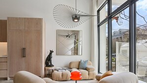 A modern living room with a sofa set, a round table, a decorative lamp, and a large window with a view. - Modern House, walk to French Quarter or the street car is a block away! (New Orleans)