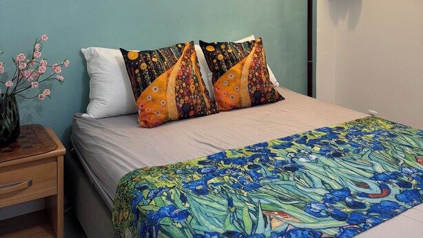 Ein Schlafzimmer mit einem Bett, einem Nachttisch, einer Lampe und drei Gemälden von Monet an der Wand.
