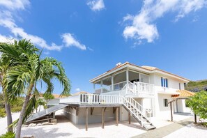 A two-story house with a balcony, a staircase, and a solar panel. - Spacious tropical villa near sea with porch (Sint Willibrordus)
