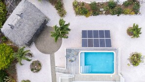 An aerial view of a resort with a swimming pool, solar panels, and a thatched-roof structure. - Spacious tropical villa near sea with porch (Sint Willibrordus)