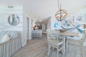A modern kitchen with a dining area, wooden flooring, and a chandelier. - Summer House 1101B | Beachfront Condo | Resort Amenities | Indoor & Outdoor Pool | My Beach Getaways (Orange Beach)