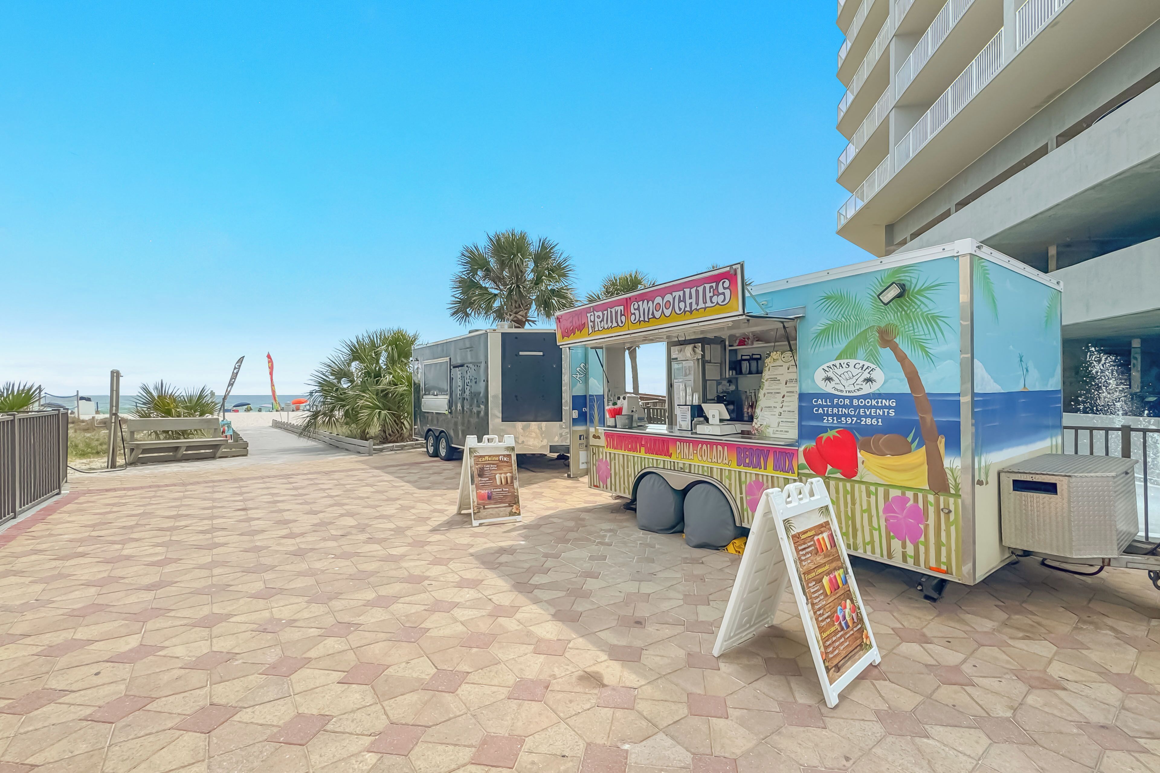 Un camion-restaurant à thème tropical, une allée piétonne et un bâtiment en arrière-plan.