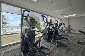 A gym with treadmills and exercise equipment, large windows with a view of the beach, and a carpeted floor. - Seawind 1804 | Beachfront | Pool | Hot Tub | My Beach Getaways (Gulf Shores)