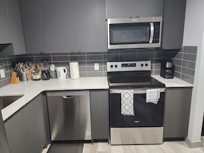Een moderne keuken met roestvrijstalen apparatuur, een vaatwasser en een koffiezetapparaat.
