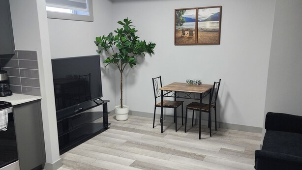 Een moderne keuken met een ingebouwde oven, een eethoek met een tafel en stoelen, een potplant en een schilderij aan de muur.