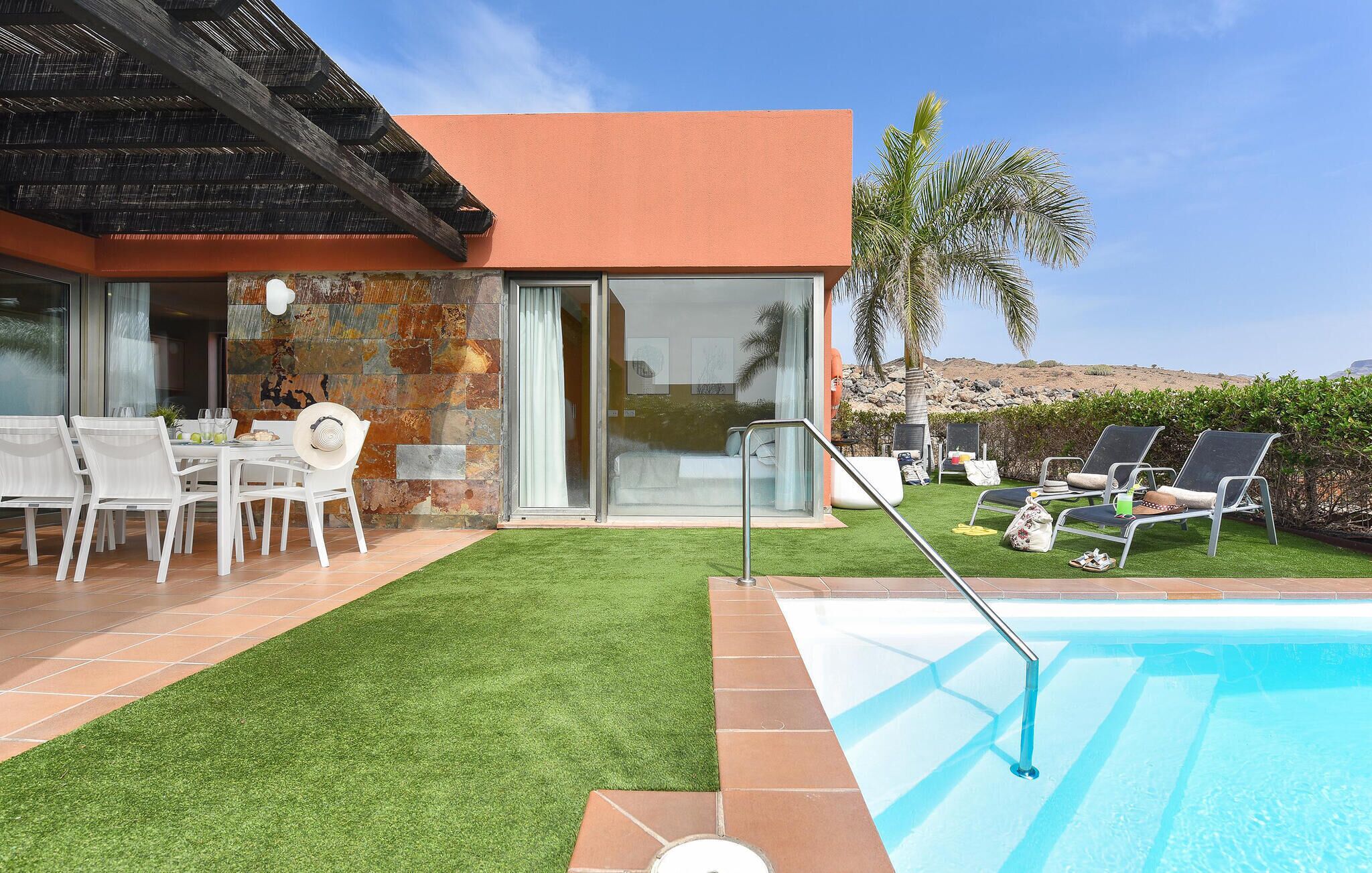 Ein modernes Haus mit Pool, Sitzgelegenheiten im Freien und Blick auf die Landschaft.