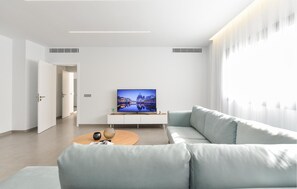 Ein modernes Wohnzimmer mit einer Couch, einem Couchtisch und einem Fernseher, der eine Stadtansicht zeigt.