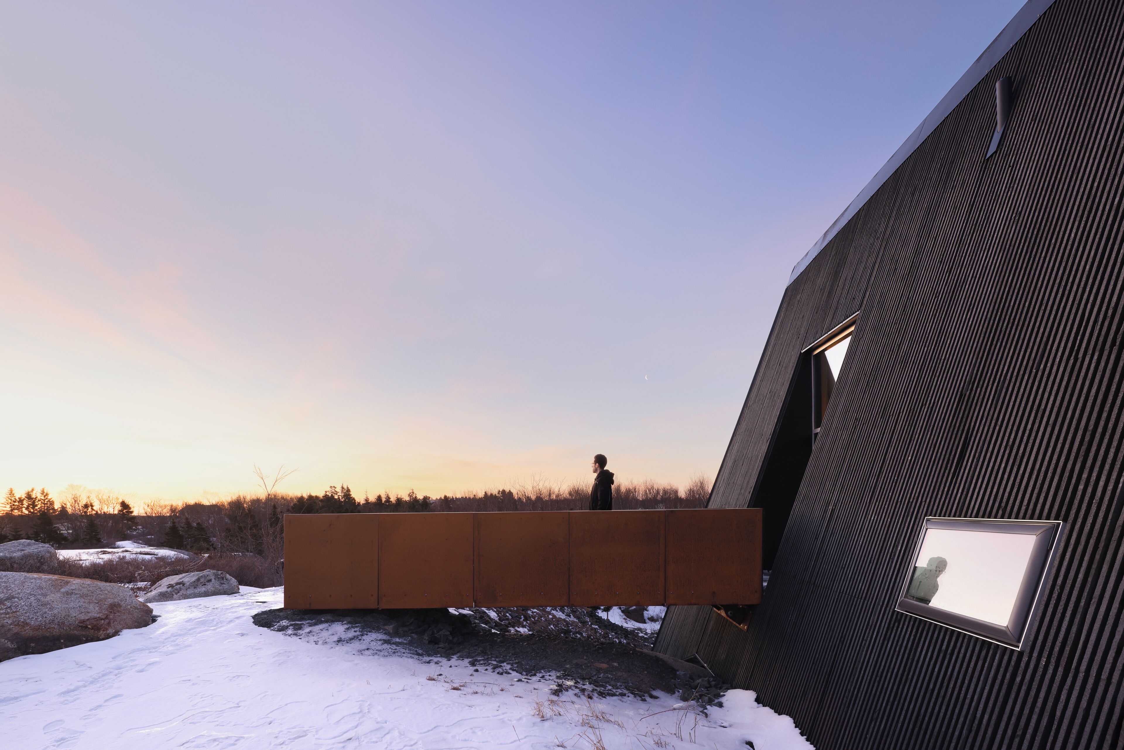 A modern building with a unique architectural design, featuring a large, flat, rectangular structure adjacent to a sloped wall with a window.
