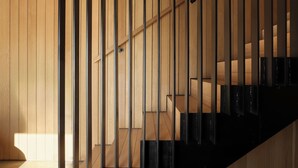Eine moderne Treppe mit Holzvertäfelung und schwarzen Geländern.
