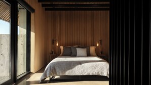 Ein Schlafzimmer mit einem Bett, zwei Nachttischen und einem großen Fenster.
