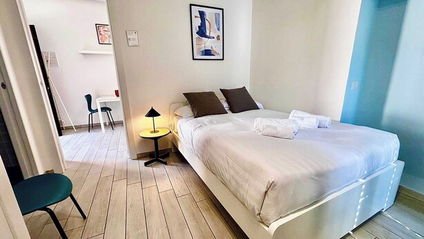 Ein Schlafzimmer mit Bett, Nachttisch, Lampe und einem Bild an der Wand.