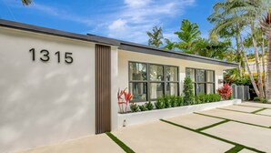 A modern building with the number 1315, large windows, and a well-maintained garden with grass and plants. - Modern Home • Pool • Near Beach & Las Olas (Fort Lauderdale)