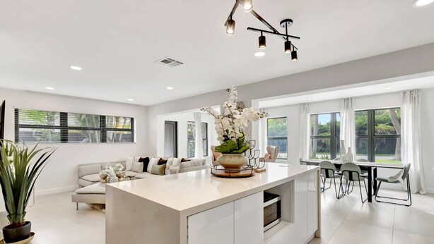 A modern kitchen with a central island, dining area, and a sofa. - Modern Home • Pool • Near Beach & Las Olas (Fort Lauderdale)
