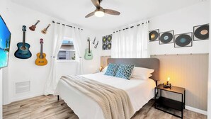 A bedroom with a bed, a nightstand, a ceiling fan, guitars on the wall, and framed records. - 2 Homes! - 4 MN to Madiera BCH - Hottub - HTD Pool (St. Petersburg)