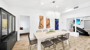 A modern dining area with a white table, black chairs, and a chandelier. - 2 Homes! - 4 MN to Madiera BCH - Hottub - HTD Pool (St. Petersburg)