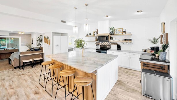 A modern kitchen with a large island, bar stools, and a built-in oven. - 2 Homes! - 4 MN to Madiera BCH - Hottub - HTD Pool (St. Petersburg)