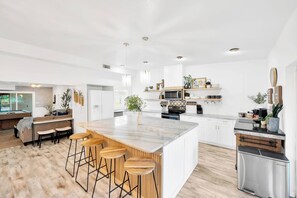 Eine moderne Küche mit einer großen Kochinsel, Barhocker und einem eingebauten Backofen.
